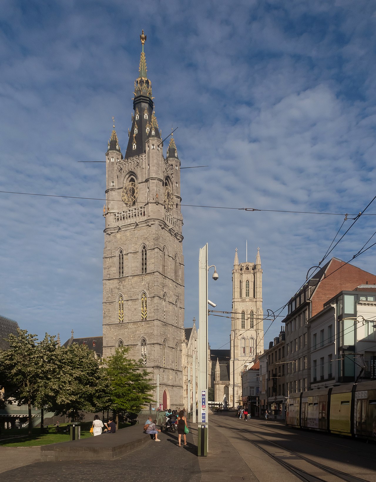 앞쪽의 겐트 벨프리와 뒤쪽의 성 바보 대성당 탑이 보이는 도심 거리 풍경