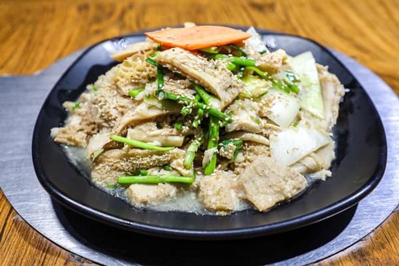 채소와 고기 결이 함께 보이는 한 접시 요리가 검은 접시에 담긴 부민옥 곁들임 메뉴