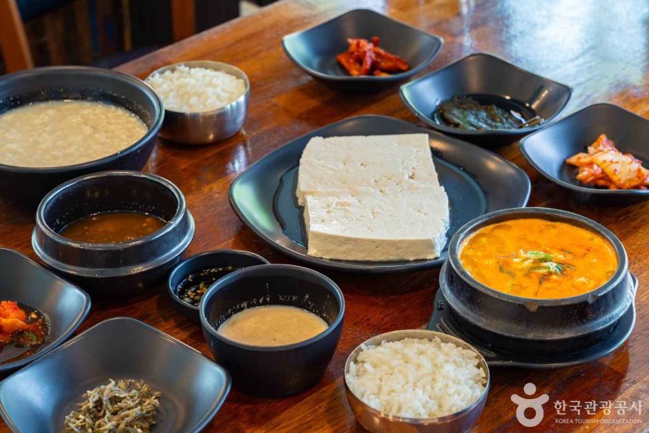 초당할머니순두부의 하얀 순두부와 째복순두부, 반찬이 함께 차려진 한 상