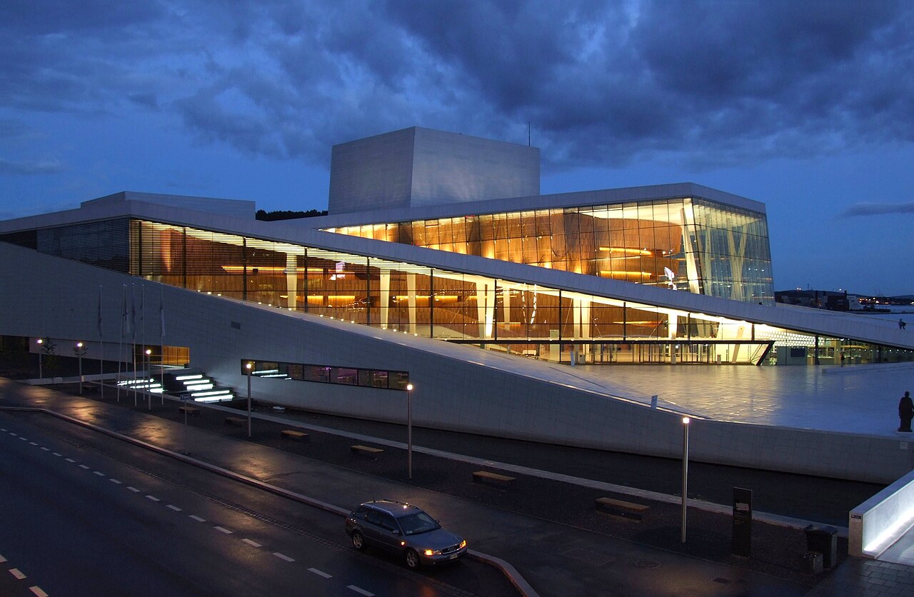 푸른 저녁 하늘 아래 오슬로 오페라하우스의 경사진 흰 대리석 지붕과 유리 파사드