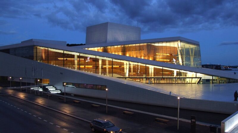 푸른 저녁 하늘 아래 오슬로 오페라하우스의 경사진 흰 대리석 지붕과 유리 파사드