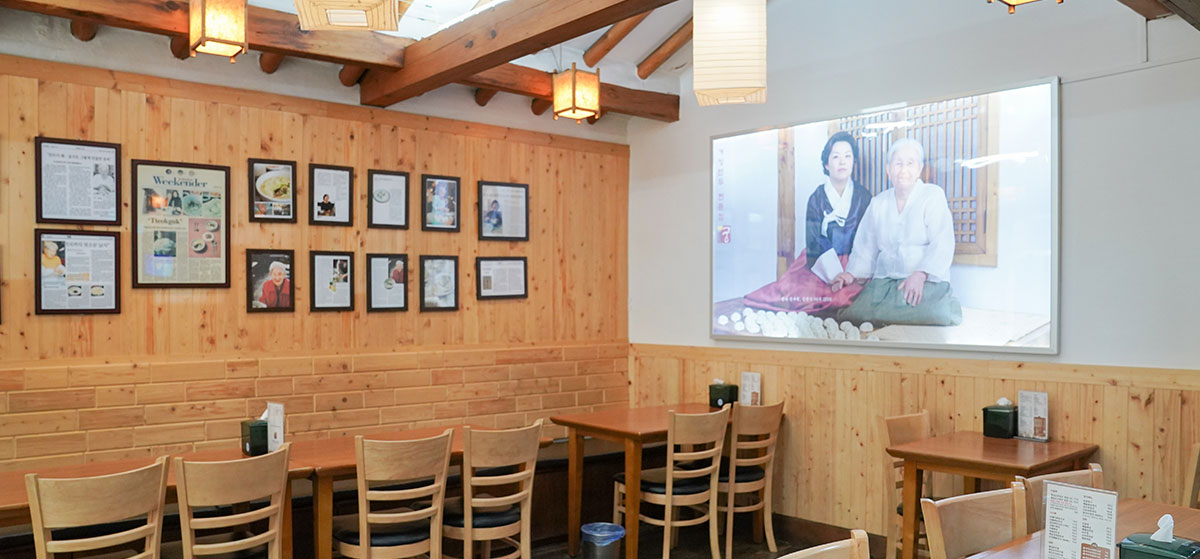 나무 벽과 테이블, 액자가 보이는 개성만두 궁 인사동 본점 실내 좌석 풍경