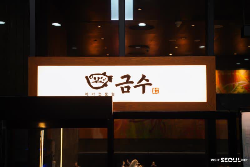 잠실 소피텔 지하 금수복국 잠실소피텔점의 물고기 로고와 금수복국 간판이 보이는 야간 표지