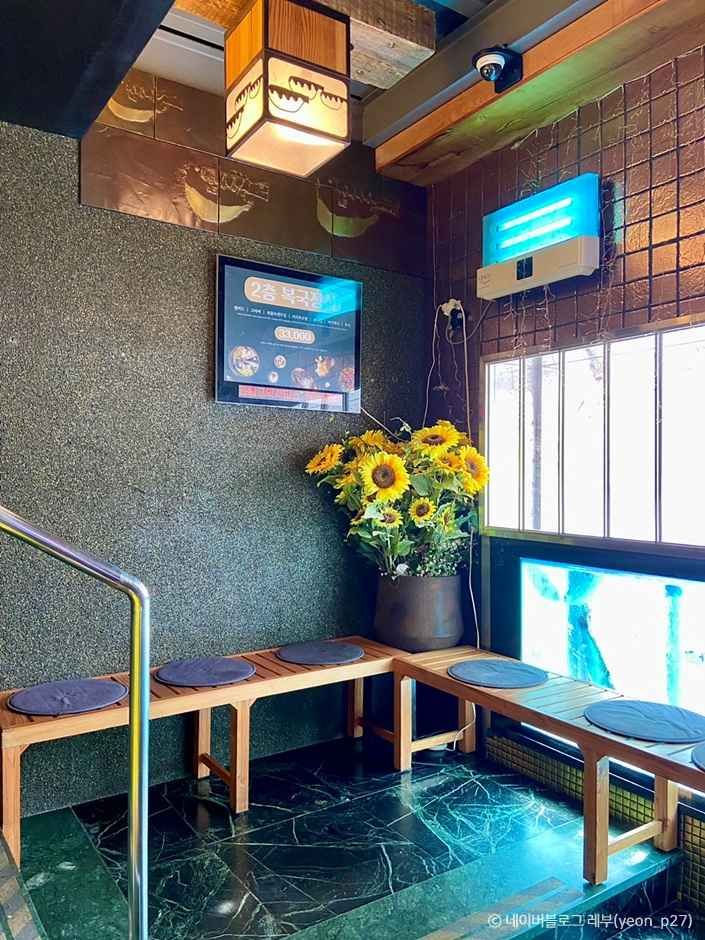 부산 금수복국 해운대본점 내부 대기 공간의 벤치와 해바라기 장식이 보이는 실내 풍경
