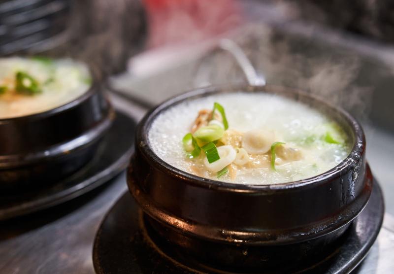 고려삼계탕의 김 오르는 삼계탕 뚝배기와 파가 올려진 국물 클로즈업