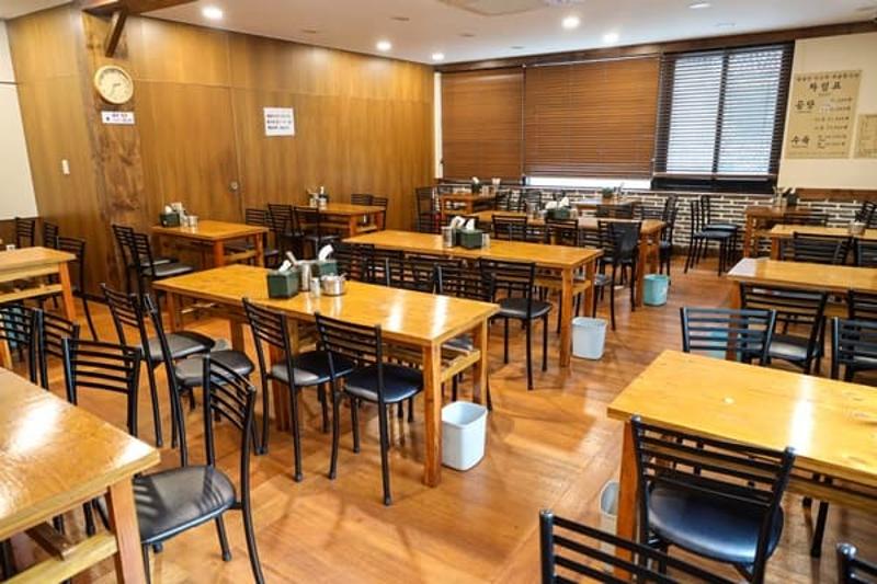 서울 명동 하동관 명동본점 내부 테이블과 검은 의자, 벽시계가 보이는 식사 공간