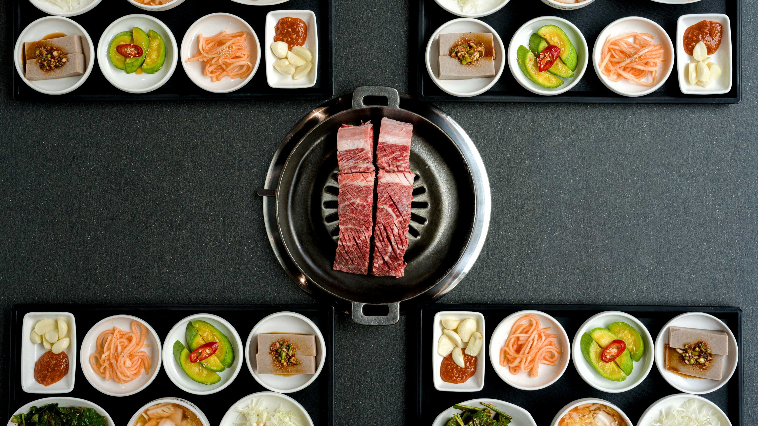 해운대암소갈비집 불판 위 생갈비와 여러 반찬이 한 상으로 차려진 테이블 장면