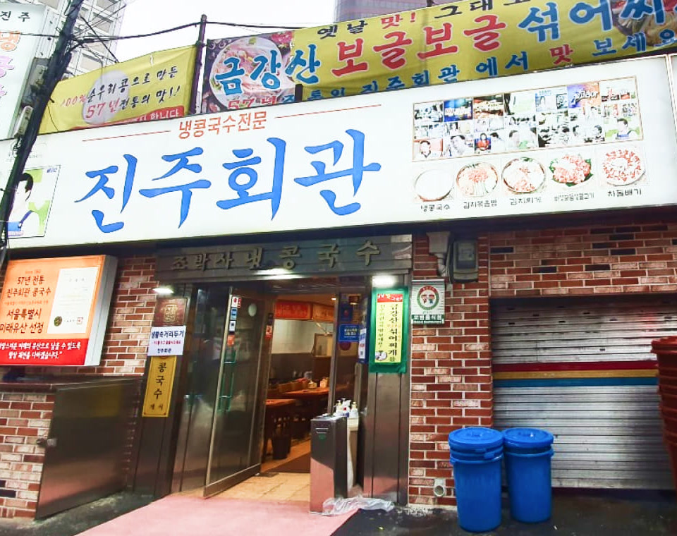 냉콩국수전문 글자와 진주회관 파란 간판, 유리 출입문이 가까이 보이는 입구 장면