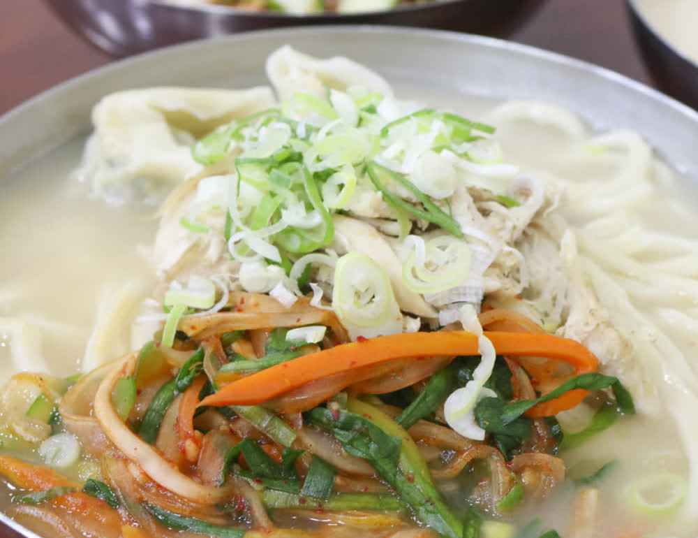 서울 여의도 진주집의 면 요리 한 상과 넓은 금속 그릇, 파 고명이 보이는 테이블