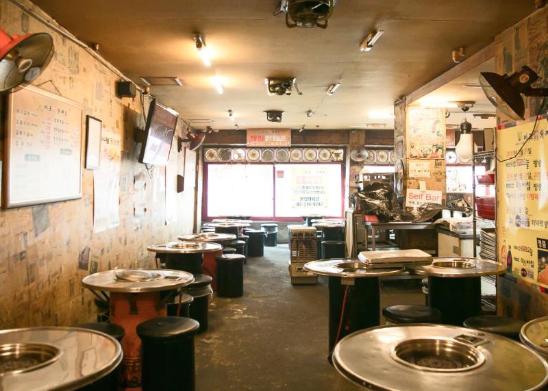 마포진짜원조최대포 실내의 둥근 불판 테이블과 낮은 스툴