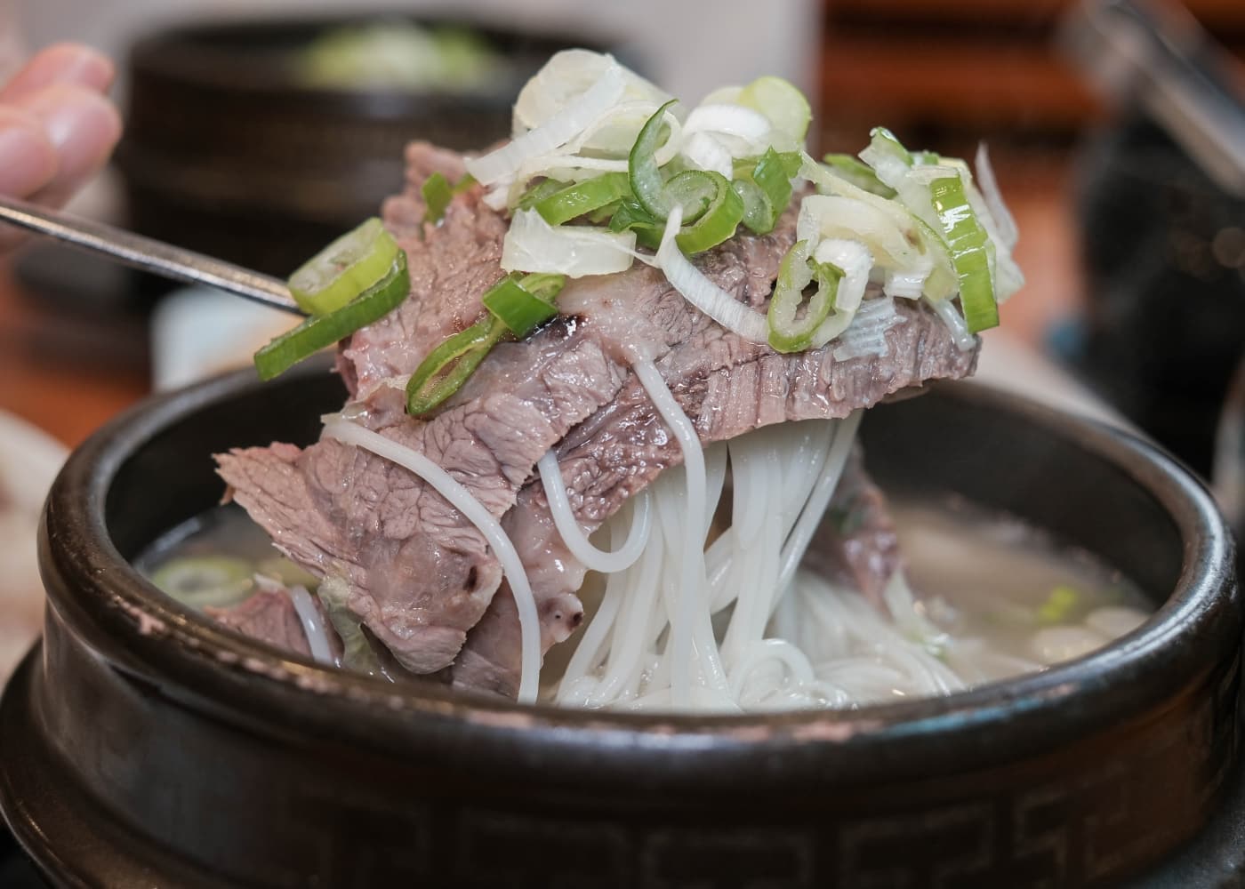 서울 마포 마포옥 소고기 국물 한 그릇에서 고기와 면, 파를 숟가락으로 들어 올린 클로즈업