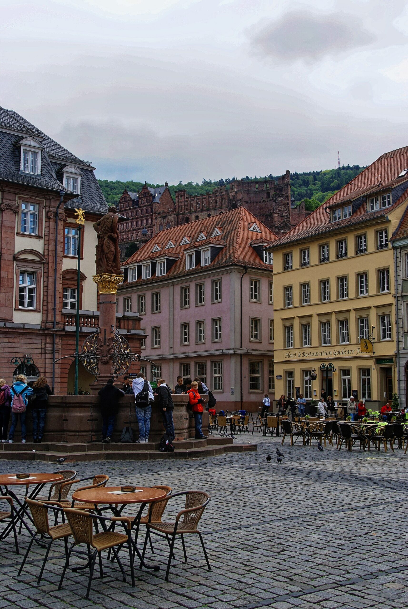 하이델베르크 마르크트광장에서 분수와 광장 너머 언덕 위 성이 보이는 풍경