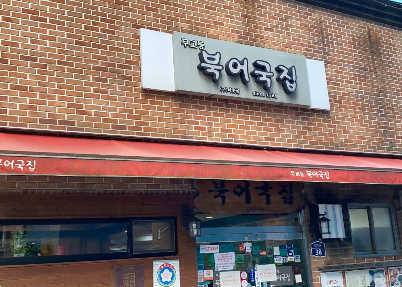 벽돌 외관과 since 1968 간판, 붉은 차양이 함께 보이는 무교동북어국집 정면