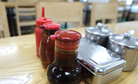 서울 오장동흥남집 본점 나무 테이블 위 양념 통과 병, 의자가 보이는 실내 디테일