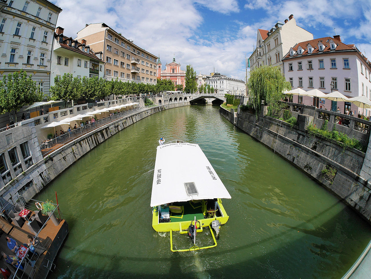 강 위 관광 보트와 강변 카페, 분홍색 교회가 보이는 류블랴나 올드타운 강변 풍경