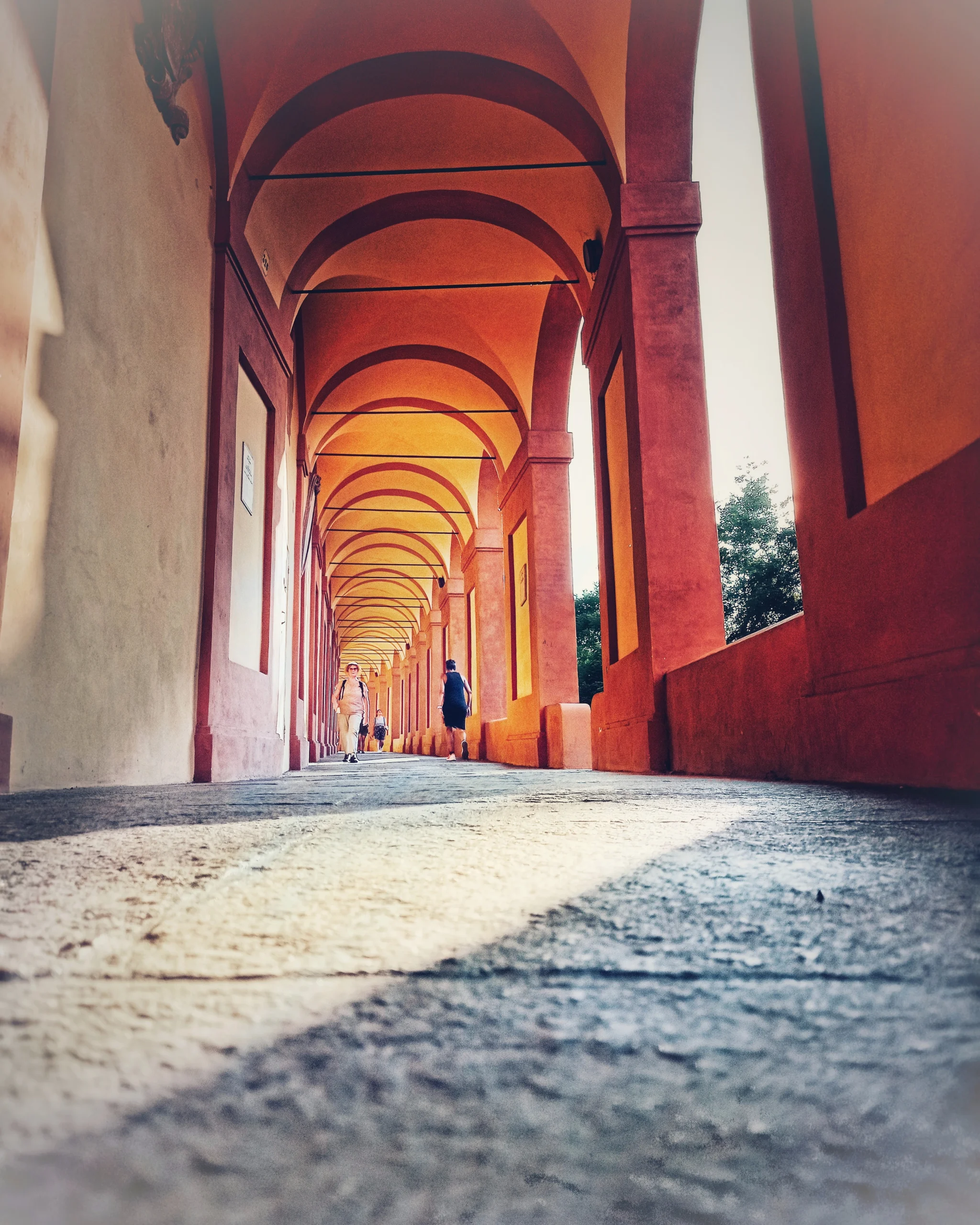 붉은 아치가 길게 이어지는 볼로냐 포르티코 아래 보행 통로 풍경