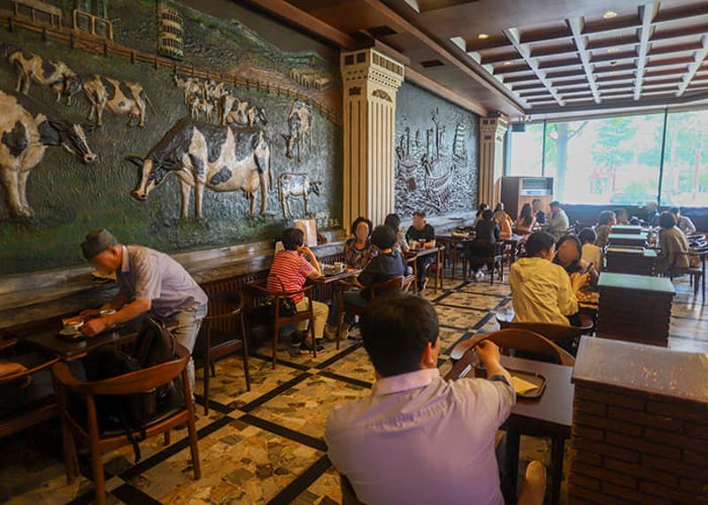 태극당 본점 카페 좌석과 손님들, 벽면 부조 장식이 보이는 실내 풍경