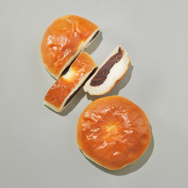 회색 배경 위에 태극당 단팥빵 두 개가 놓여 있고 하나는 잘려 속이 드러난 장면