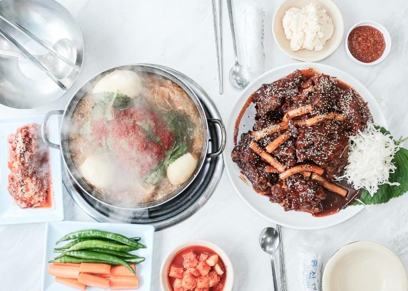태조대림감자국의 감자국 냄비와 붉은 뼈 요리, 밑반찬이 함께 놓인 한 상