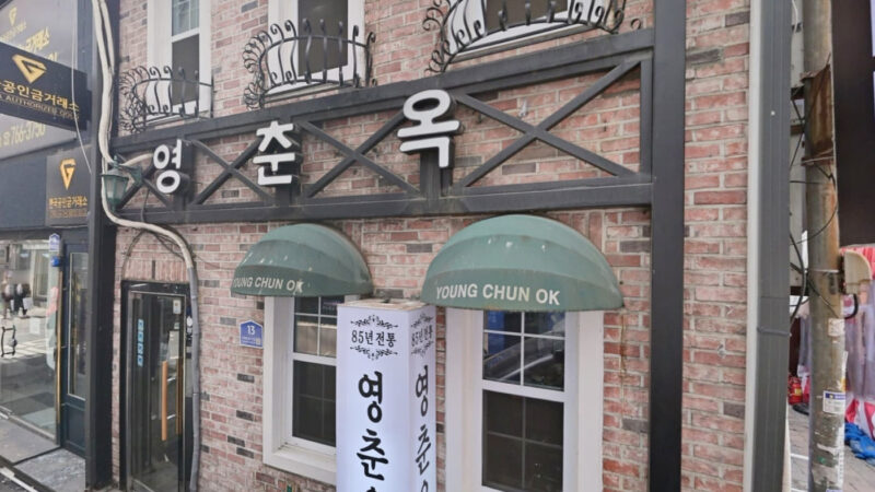 종로3가 골목에 있는 영춘옥 벽돌 외관과 초록색 차양, 세로 간판이 보이는 입구