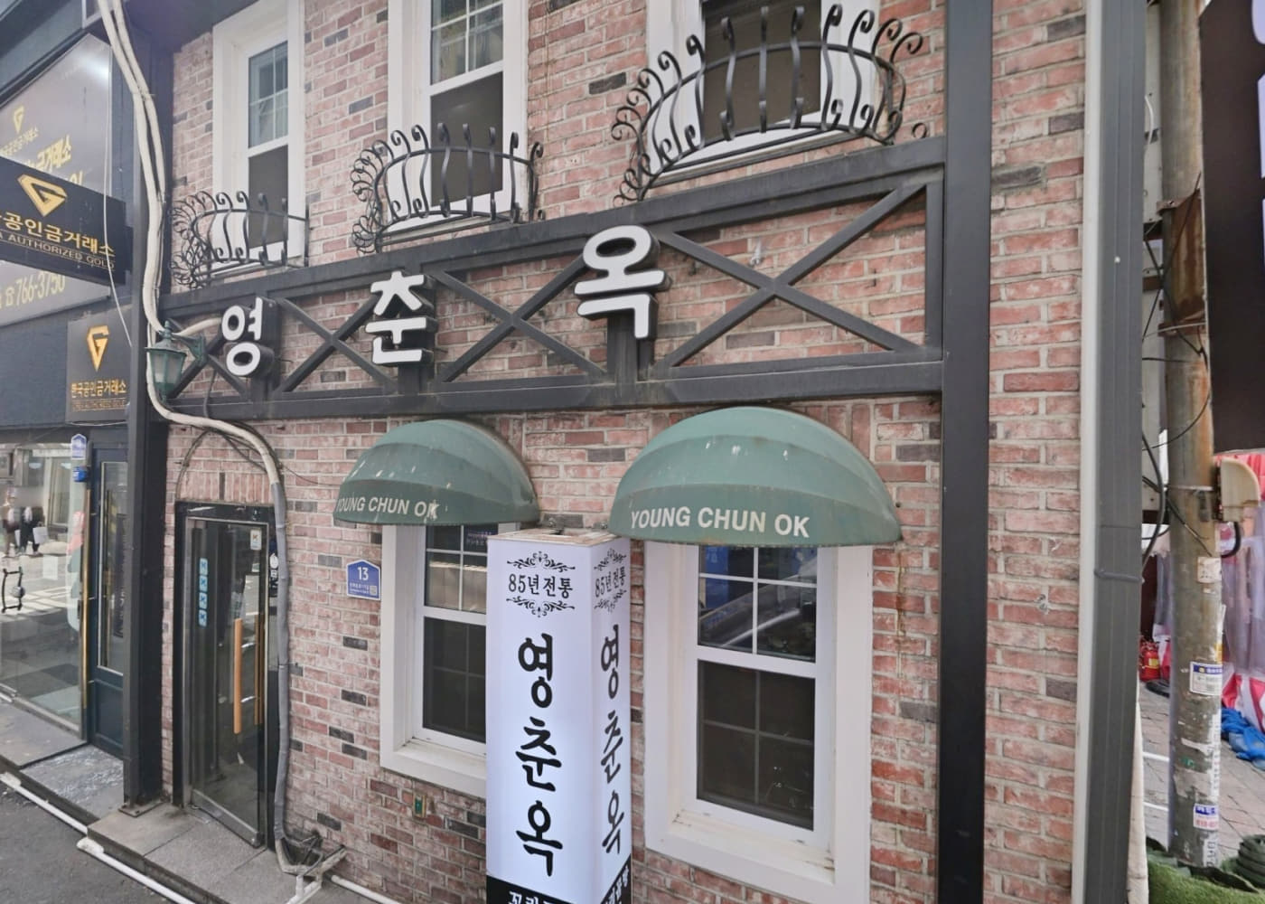 종로3가 골목에 있는 영춘옥 벽돌 외관과 초록색 차양, 세로 간판이 보이는 입구