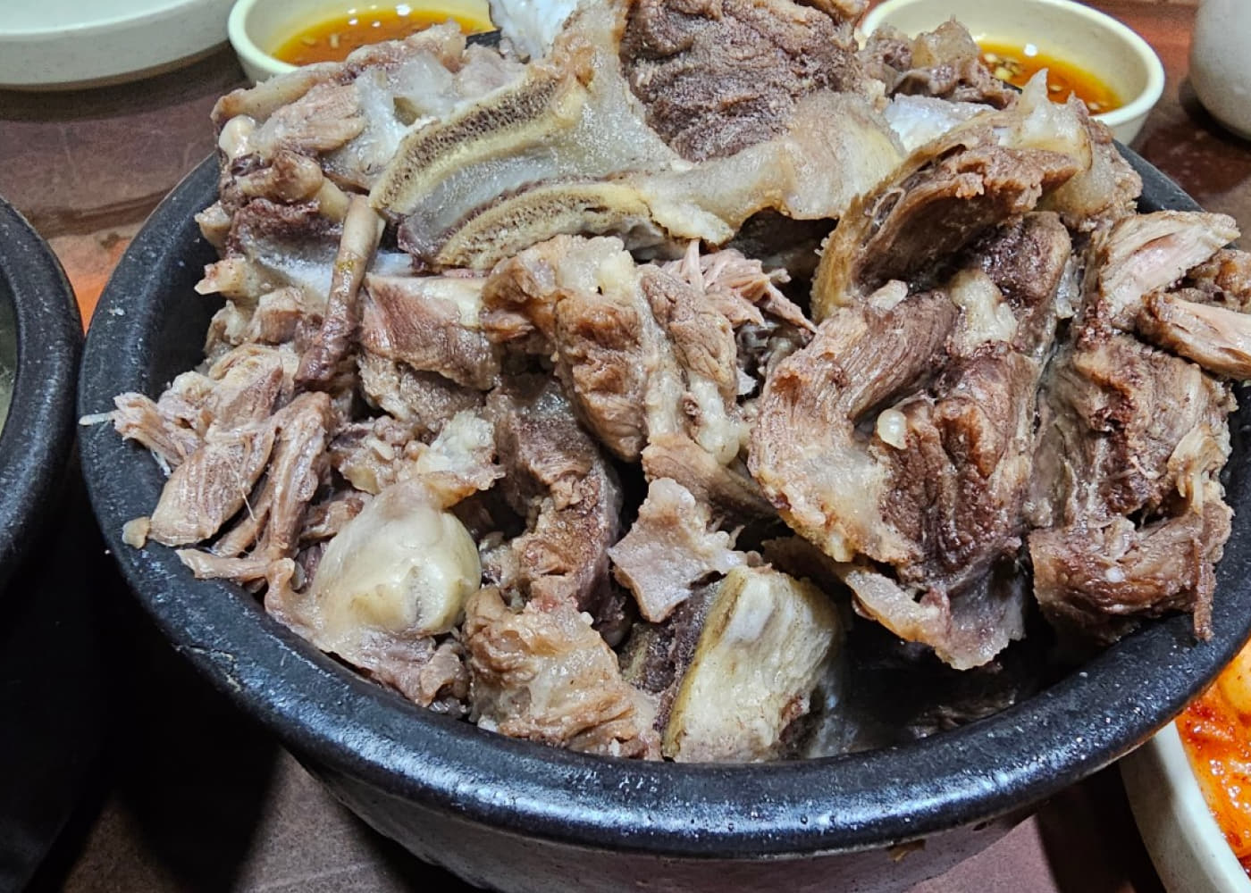 검은 그릇에 뼈째 올라온 고기 메뉴와 양념장이 함께 놓인 영춘옥 식탁
