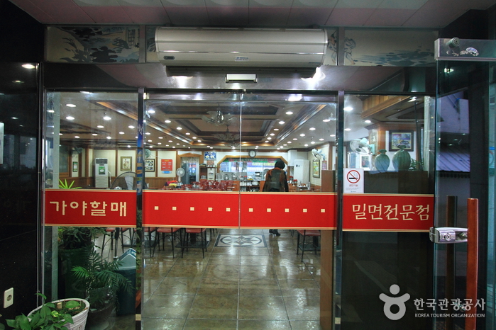 가야할매밀면 입구 유리문에 붉은 글씨 간판이 붙어 있고 실내 테이블이 보이는 정면