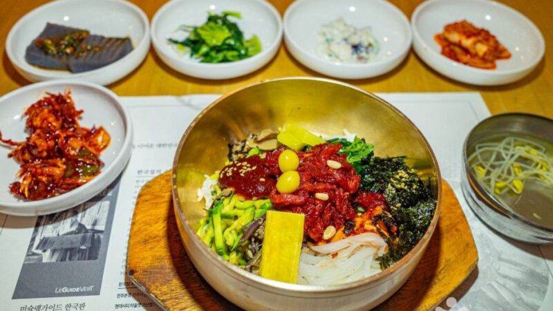 놋그릇에 담긴 한국집 전주비빔밥과 콩나물국, 반찬이 함께 놓인 한 상
