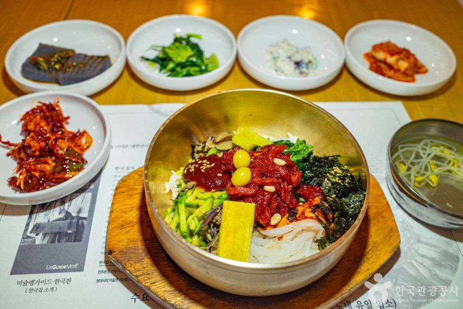 놋그릇에 담긴 한국집 전주비빔밥과 콩나물국, 반찬이 함께 놓인 한 상