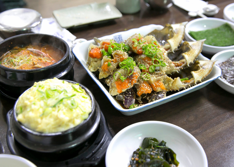파 고명이 올라간 간장게장 접시와 여러 반찬이 보이는 진미식당 상차림