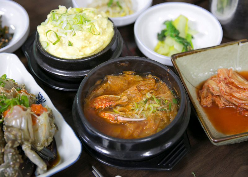 붉은 국물 냄비와 계란찜, 게장 접시가 함께 보이는 진미식당 상차림