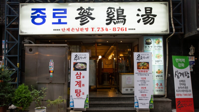 서울 종로 종로삼계탕 입구의 밝은 간판과 메뉴 보드, 계단이 보이는 외관