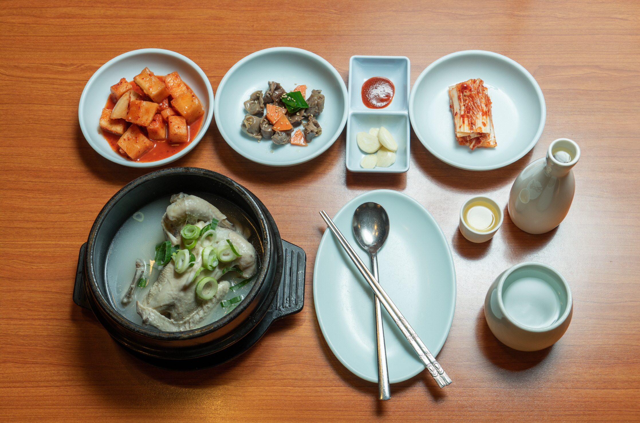 종로삼계탕의 삼계탕 한 상과 김치, 깍두기, 마늘, 작은 잔이 함께 놓인 상차림 전체