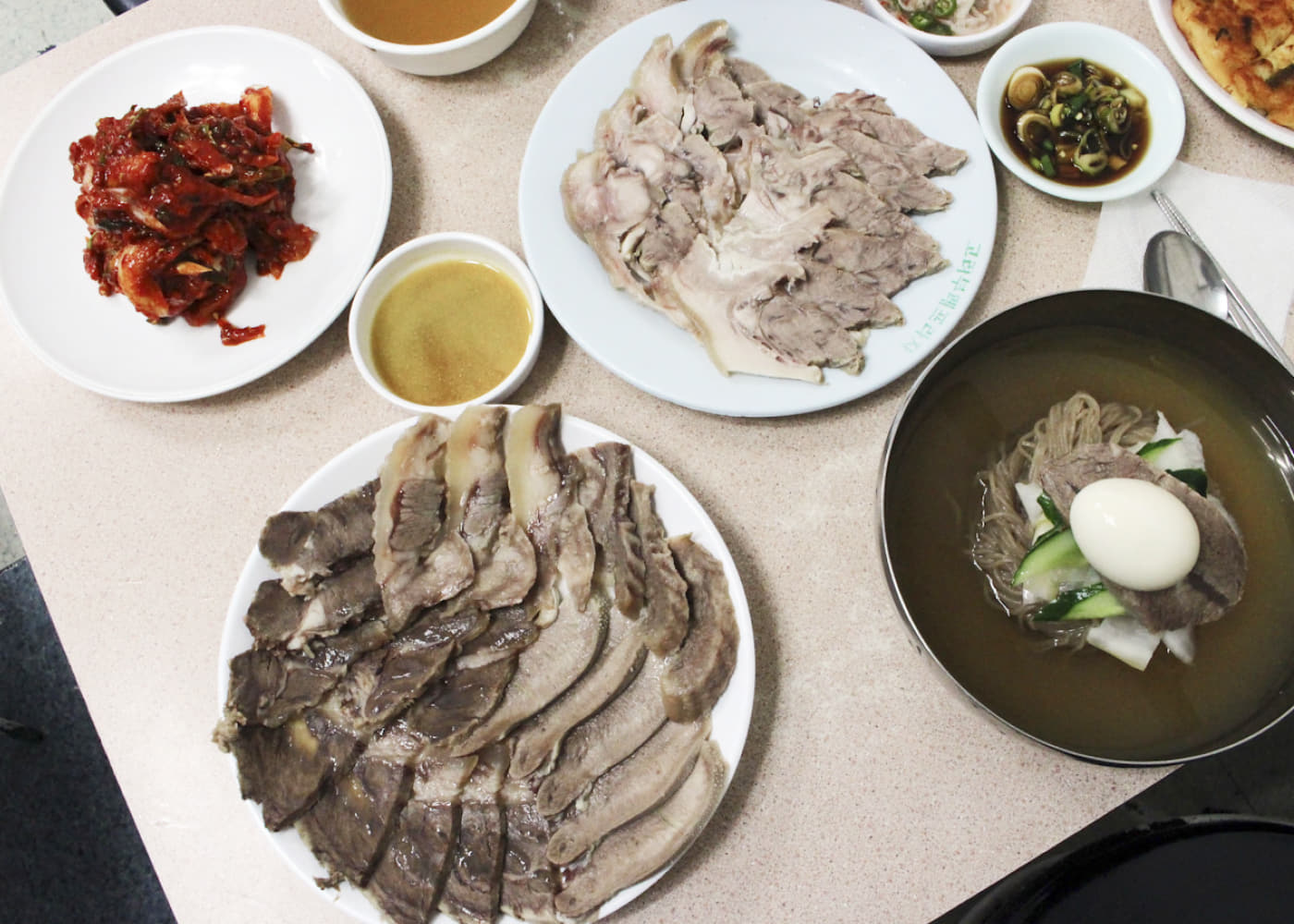 유진식당 냉면과 고기 접시, 김치와 소스가 함께 놓인 한 상