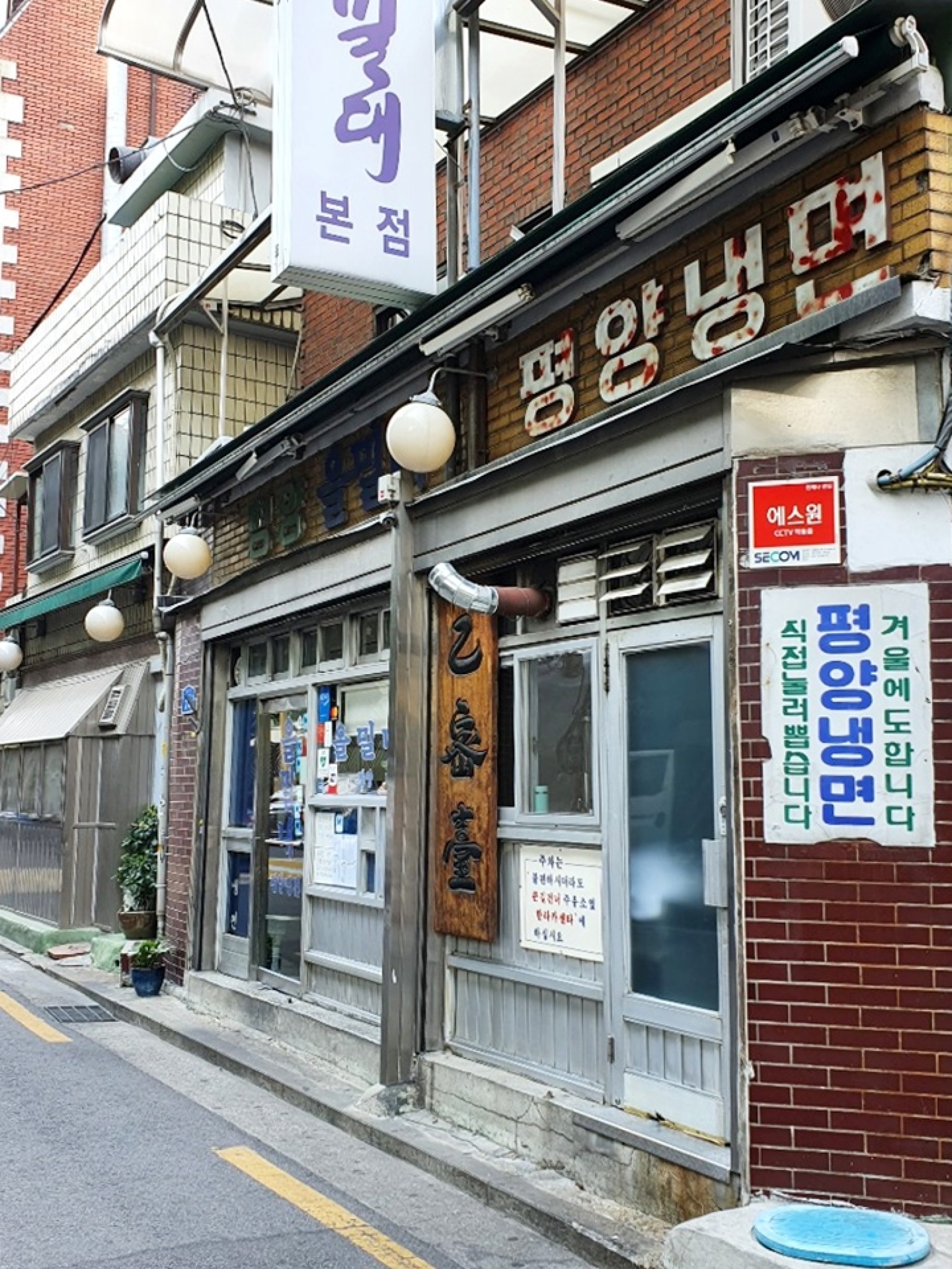 마포 염리동 을밀대 본점 외관과 낡은 벽면, 붉은 차양이 함께 보이는 모습