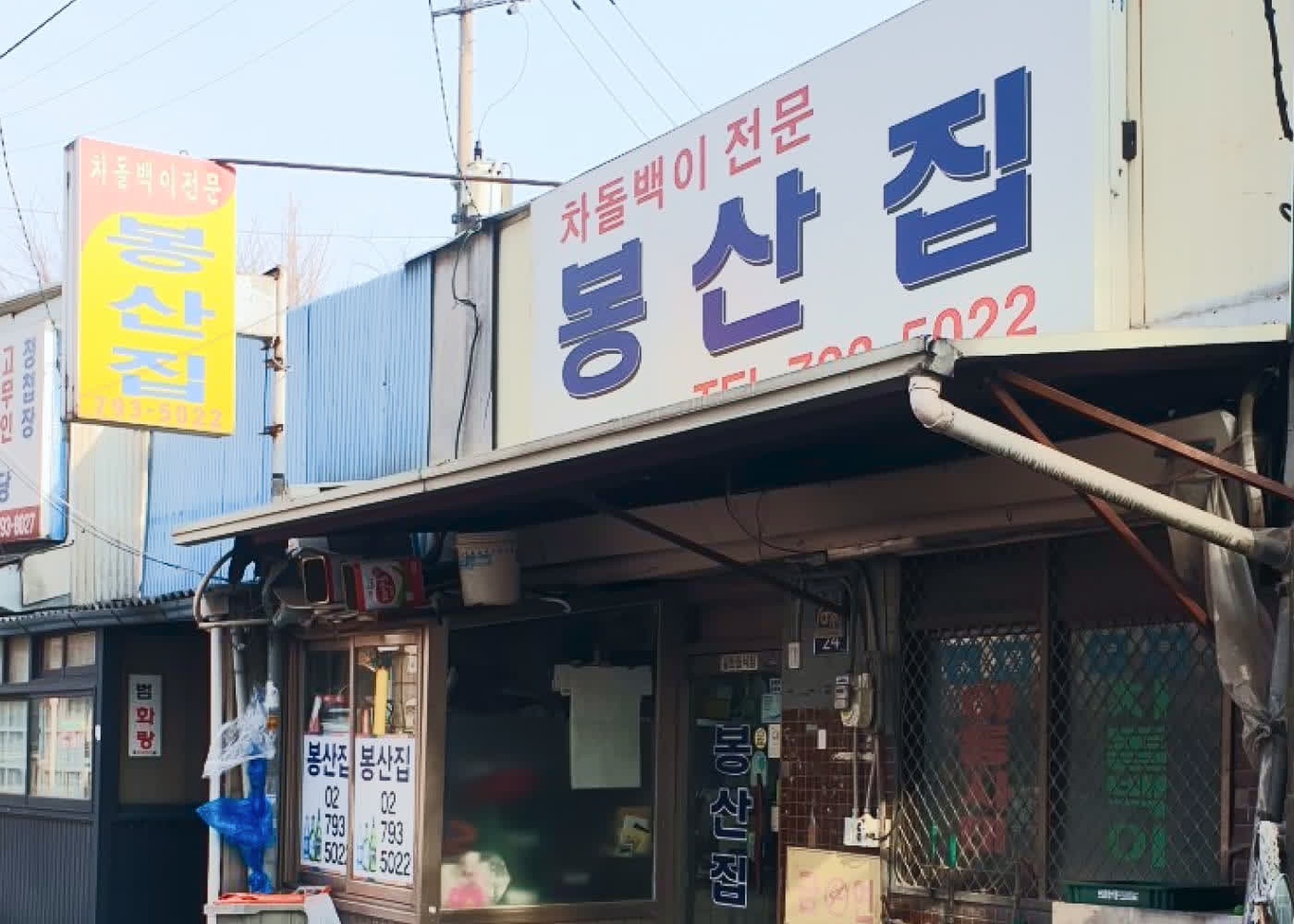 봉산집 외관과 골목 앞 간판이 보이는 모습